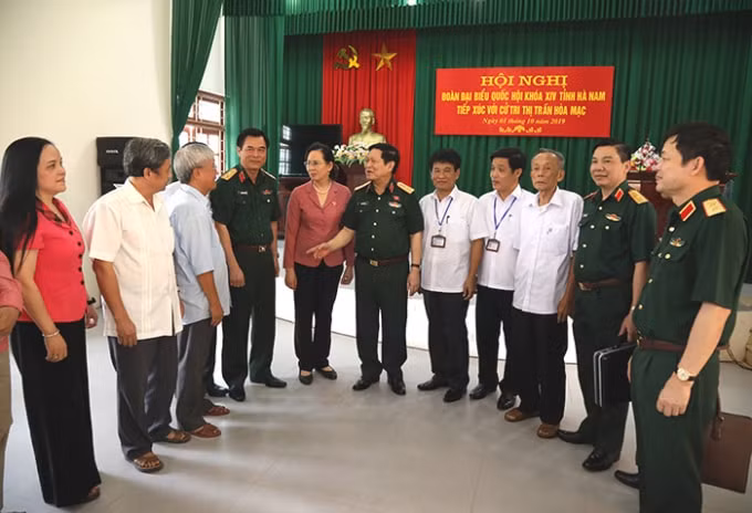 Đại tướng Ngô Xuân Lịch và các đại biểu, cử tri trao đổi bên lề hội nghị. Ảnh: BQP.