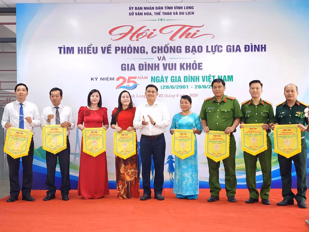 Ông Trần Công Khánh, Phó Giám đốc Sở Văn hóa, Thể thao và Du lịch tỉnh Vĩnh Long trao cờ lưu niệm cho các đội tham gia Hội thi tìm hiểu về phòng, chống bạo lực gia đình