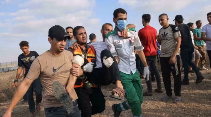 Các nhân viên y tế và người biểu tình Palestine sơ tán một người đàn ông bị thương trong cuộc đụng độ với lực lượng an ninh Israel hôm thứ Bảy - Ảnh: AFP