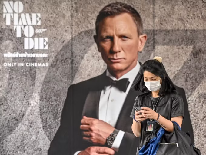 Một người phụ nữ đeo khẩu trang đi ngang qua tấm áp phích cho bộ phim James Bond mới 
