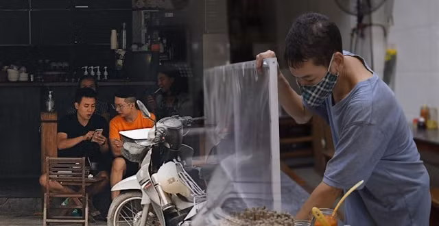 Người kinh doanh quán ăn ở Hà Nội lắp tấm kính chắn để phòng chống dịch Covid-19. Ảnh: TL.