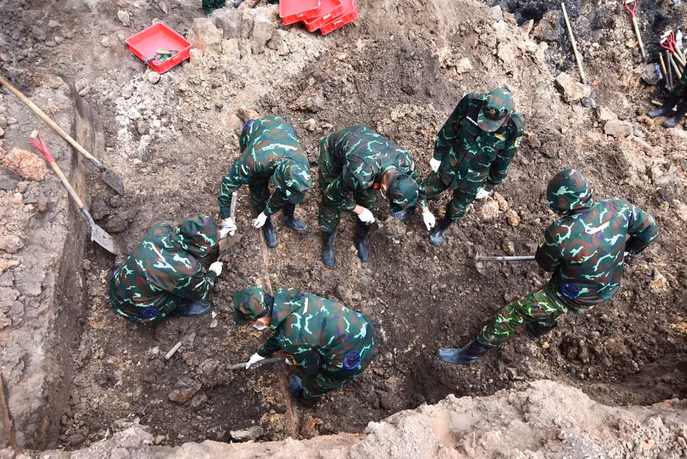 Cán bộ, chiến sĩ cẩn trọng kiểm tra, sàng lọc từng lớp đất trong quá trình tìm kiếm hài cốt liệt sĩ. Ảnh TTXVN.